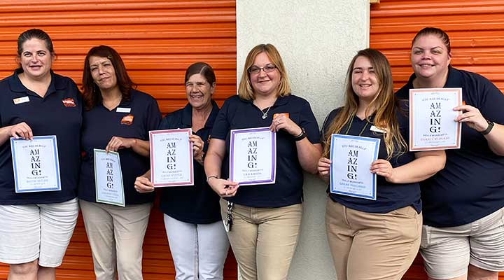 public storage property managers holding paper certificates that say amazing